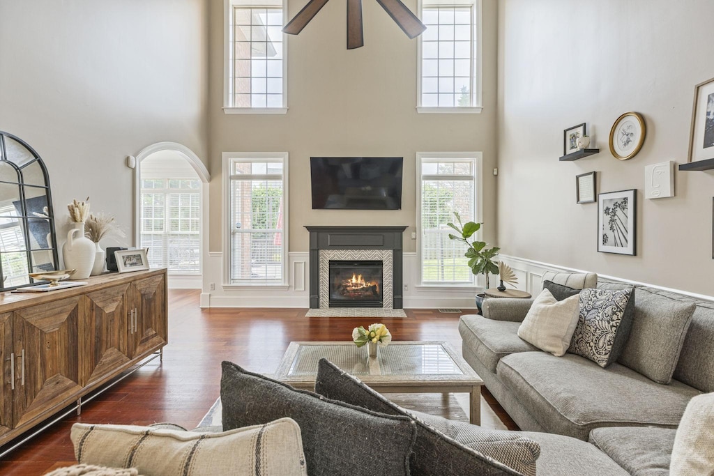 5579 Hill Rd, Brentwood, TN 37027 - living area with a high ceiling, dark wood finished floors, a ceiling fan, a tiled fireplace, and a wainscoted wall