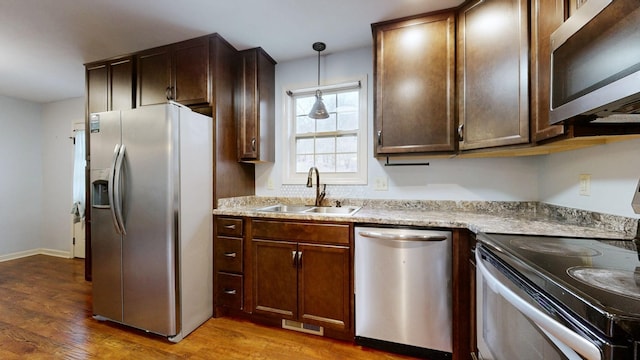3388 Budds Creek Rd, Palmyra, TN 37142 - kitchen featuring appliances with stainless steel finishes, wood finished floors, light countertops, hanging light fixtures, and dark brown cabinetry