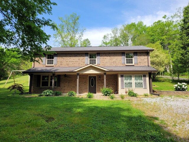 3388 Budds Creek Rd, Palmyra, TN 37142 - traditional home with a front lawn, a ceiling fan, and brick siding