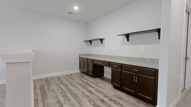 1012 Michaela Cir, Clarksville, TN 37043 - kitchen featuring open shelves, dark brown cabinetry, light wood-style flooring, light stone counters, and built in desk