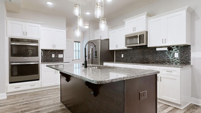 1012 Michaela Cir, Clarksville, TN 37043 - kitchen featuring appliances with stainless steel finishes, light wood-style flooring, white cabinetry, an island with sink, and recessed lighting