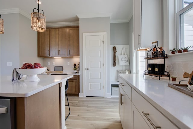 5219 Gladecress Ln, Hermitage, TN 37076 - kitchen with light wood-style flooring, crown molding, light countertops, brown cabinetry, and hanging light fixtures