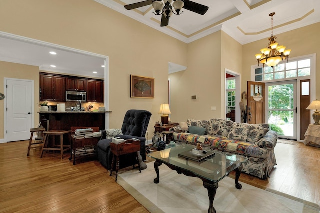7003 Neville Dr, Ooltewah, TN 37363 - living area with a towering ceiling, crown molding, ceiling fan, light wood-type flooring, and a chandelier