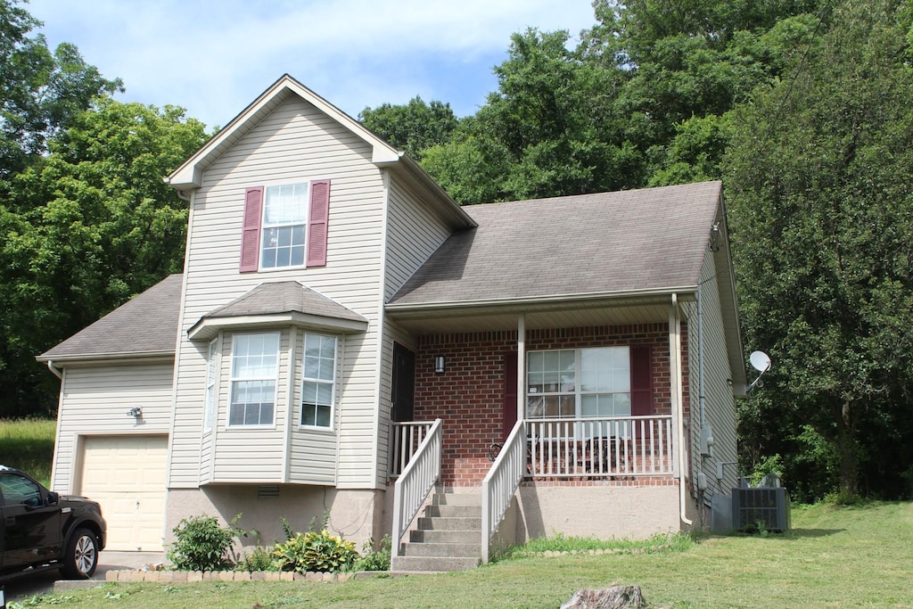 4705 Ashley Way, Hermitage, TN 37076 - view of front of home featuring roof with shingles, covered porch, a front yard, a garage, and brick siding