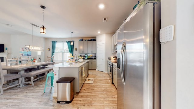 308 Whisper Wood Way, Lebanon, TN 37087 - kitchen with stainless steel appliances, light wood-style flooring, an island with sink, pendant lighting, and light countertops