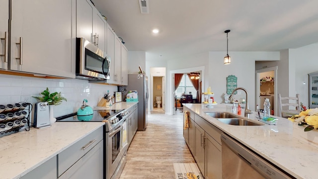 308 Whisper Wood Way, Lebanon, TN 37087 - kitchen featuring stainless steel appliances, light wood finished floors, pendant lighting, tasteful backsplash, and light stone counters