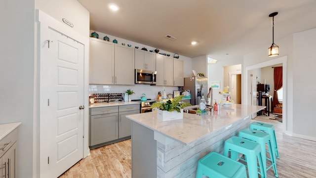 308 Whisper Wood Way, Lebanon, TN 37087 - kitchen with appliances with stainless steel finishes, light wood-type flooring, gray cabinets, backsplash, and hanging light fixtures