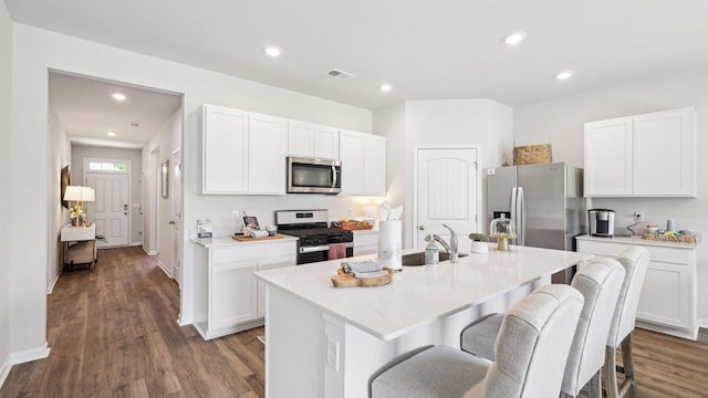 99 Hartmann Crossing Dr, Lebanon, TN 37087 - kitchen with appliances with stainless steel finishes, a kitchen breakfast bar, wood finished floors, an island with sink, and white cabinetry