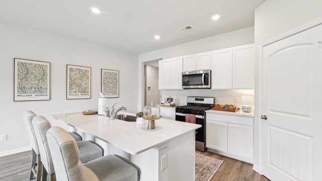 99 Hartmann Crossing Dr, Lebanon, TN 37087 - kitchen featuring appliances with stainless steel finishes, an island with sink, white cabinets, light countertops, and light wood-type flooring