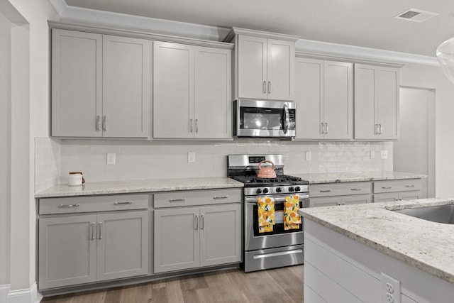 10787 Prairie Lake Dr, Apison, TN 37302 - kitchen featuring stainless steel appliances, gray cabinetry, wood finished floors, crown molding, and light stone countertops