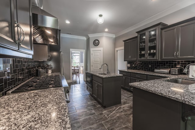 1652 Lantana Dr, Thompsons Station, TN 37179 - kitchen featuring wall chimney range hood, crown molding, dark stone counters, a center island with sink, and backsplash