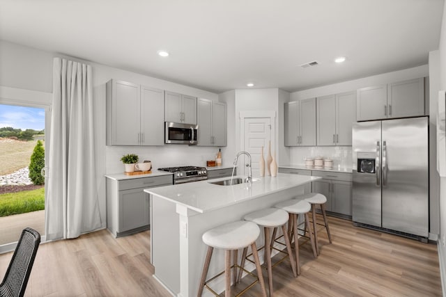 7214 Hanworth St, Fairview, TN 37062 - kitchen featuring appliances with stainless steel finishes, gray cabinets, a kitchen breakfast bar, light wood finished floors, and tasteful backsplash