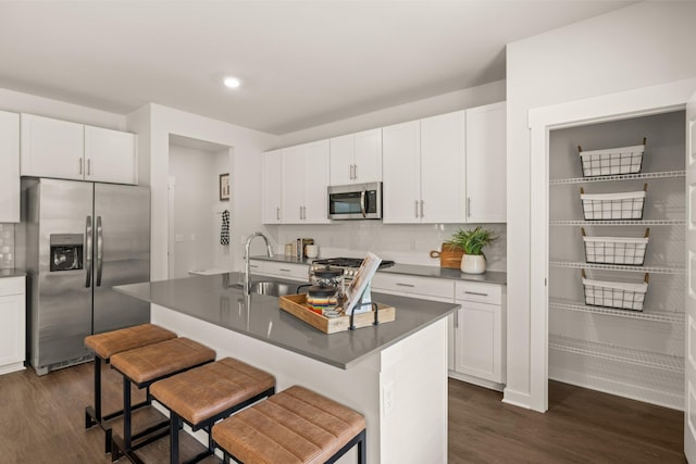 7212 Hanworth St, Fairview, TN 37062 - kitchen with appliances with stainless steel finishes, dark wood-type flooring, a kitchen breakfast bar, dark countertops, and white cabinetry