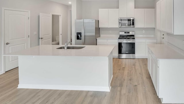88 Hartmann Crossing Dr, Lebanon, TN 37087 - kitchen featuring appliances with stainless steel finishes, light wood-type flooring, white cabinets, a center island with sink, and light countertops