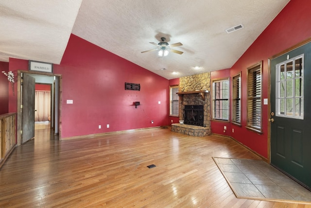 183 Jerry Smith Rd, Indian Mound, TN 37079 - unfurnished living room featuring lofted ceiling, a textured ceiling, a ceiling fan, hardwood / wood-style floors, and a stone fireplace