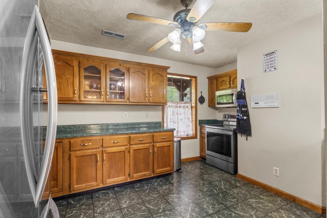 183 Jerry Smith Rd, Indian Mound, TN 37079 - kitchen with appliances with stainless steel finishes, brown cabinets, dark countertops, ceiling fan, and a textured ceiling