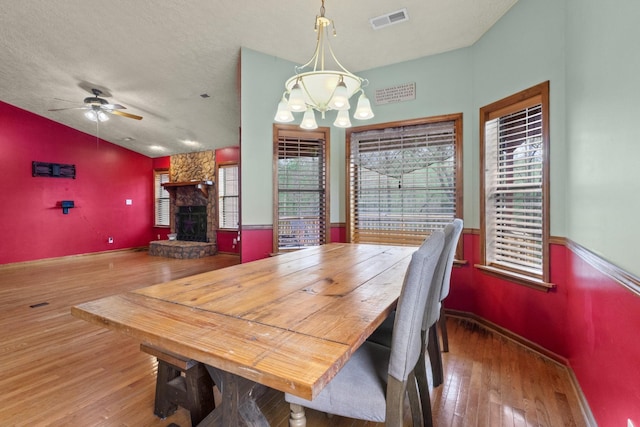 183 Jerry Smith Rd, Indian Mound, TN 37079 - dining room with wood finished floors, a stone fireplace, a chandelier, and ceiling fan