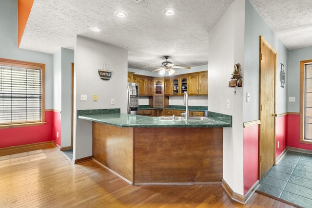 183 Jerry Smith Rd, Indian Mound, TN 37079 - kitchen featuring fridge, a textured ceiling, brown cabinets, glass insert cabinets, and dark countertops