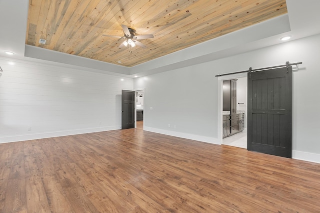 3945 Hartsville Rd, Lafayette, TN 37083 - empty room with a barn door, a tray ceiling, ceiling fan, wood ceiling, and light wood-style floors