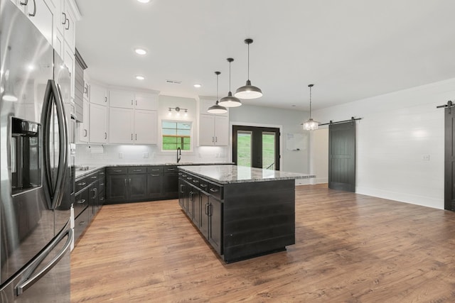 3945 Hartsville Rd, Lafayette, TN 37083 - kitchen featuring stainless steel fridge with ice dispenser, a barn door, light stone countertops, white cabinetry, and recessed lighting