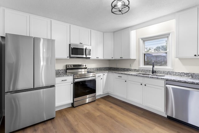 222 Jackson St, Lawrenceburg, TN 38464 - kitchen with stainless steel appliances, dark wood finished floors, light stone countertops, white cabinets, and a textured ceiling