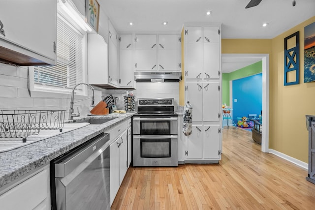314 W 2nd St, Jasper, TN 37347 - kitchen featuring stainless steel appliances, under cabinet range hood, white cabinetry, light wood-type flooring, and backsplash
