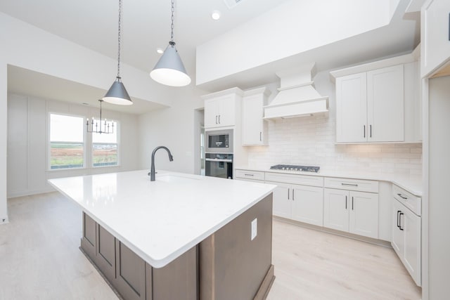 5416 Bridgemore Blvd, Murfreesboro, TN 37129 - kitchen featuring black oven, premium range hood, stainless steel microwave, light wood-type flooring, and decorative backsplash