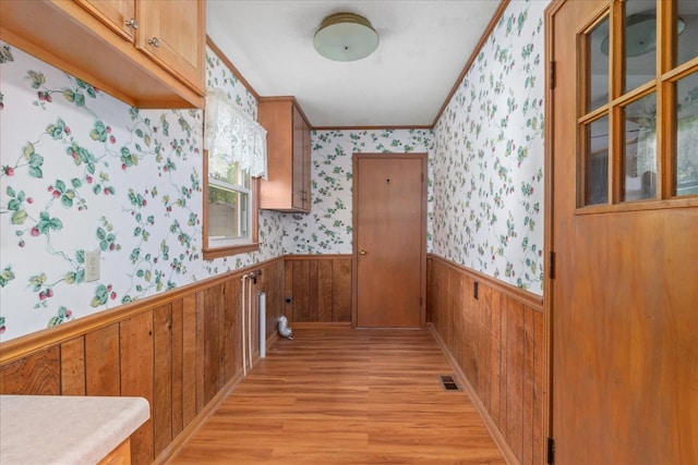 718 Midway St, Lewisburg, TN 37091 - kitchen featuring light wood-type flooring, wallpapered walls, a wainscoted wall, ornamental molding, and brown cabinetry