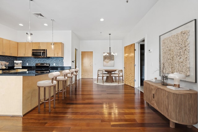 2201 8th Ave S Unit 306, Nashville, TN 37204 - kitchen with appliances with stainless steel finishes, dark wood-style floors, dark countertops, tasteful backsplash, and a breakfast bar