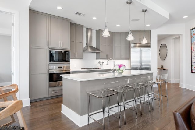20 Rutledge St Unit 407, Nashville, TN 37210 - kitchen featuring built in appliances, gray cabinets, wall chimney exhaust hood, dark wood-style floors, and recessed lighting