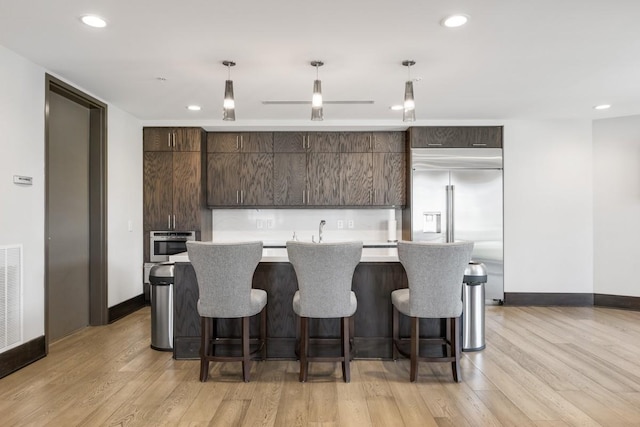 20 Rutledge St Unit 407, Nashville, TN 37210 - kitchen with dark brown cabinets, built in refrigerator, a center island, light wood-type flooring, and light countertops