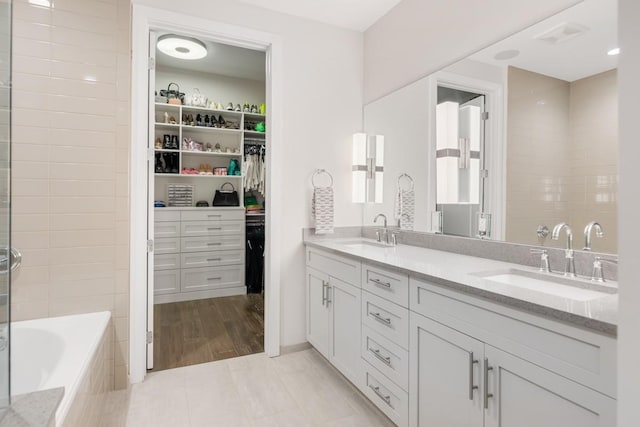 20 Rutledge St Unit 407, Nashville, TN 37210 - bathroom featuring double vanity, tiled bath, a walk in closet, and tile patterned flooring