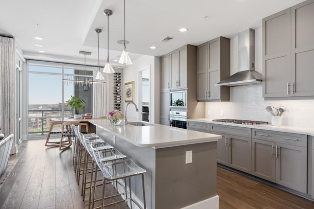20 Rutledge St Unit 407, Nashville, TN 37210 - kitchen with gray cabinetry, wall chimney exhaust hood, appliances with stainless steel finishes, dark wood-style floors, and recessed lighting