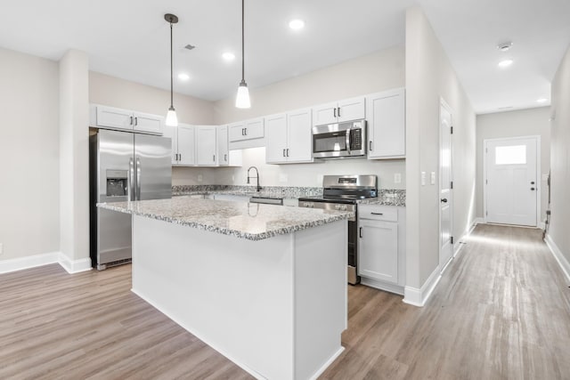 208 W Fallow Ct, Clarksville, TN 37040 - kitchen with appliances with stainless steel finishes, light wood finished floors, a kitchen island, light stone countertops, and decorative light fixtures