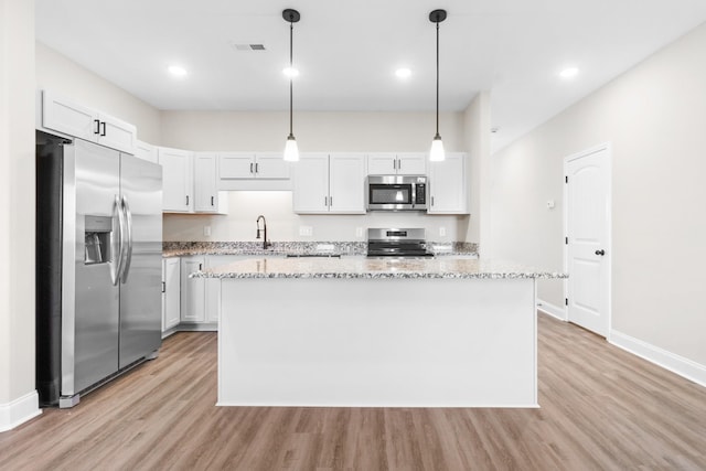 208 W Fallow Ct, Clarksville, TN 37040 - kitchen with appliances with stainless steel finishes, light wood-type flooring, a kitchen island, light stone counters, and white cabinets