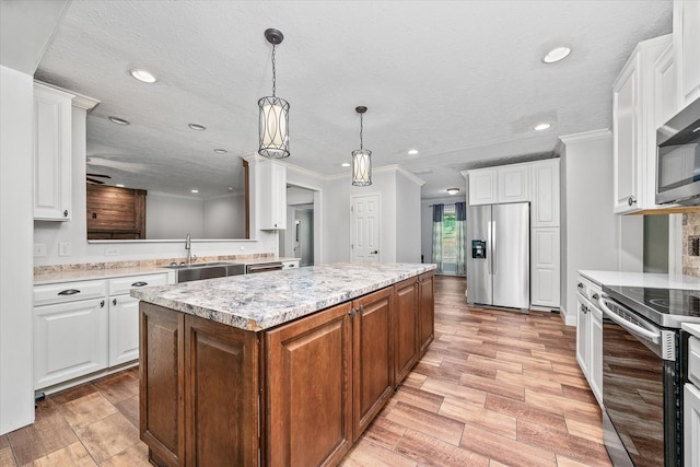 1901 Rickman Rd, Livingston, TN 38570 - kitchen with appliances with stainless steel finishes, a kitchen island, light wood-style flooring, white cabinets, and ornamental molding