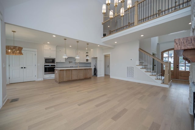 5077B Florence Rd, Murfreesboro, TN 37129 - kitchen featuring appliances with stainless steel finishes, a chandelier, open floor plan, light wood-style flooring, and a high ceiling
