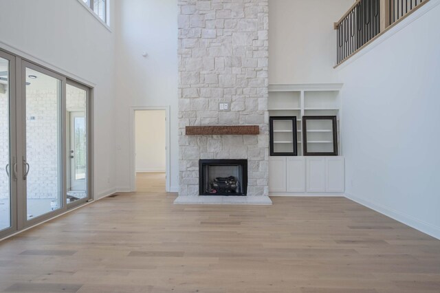 5077A Florence Rd, Murfreesboro, TN 37129 - unfurnished living room with wood finished floors, a towering ceiling, a fireplace, and built in shelves