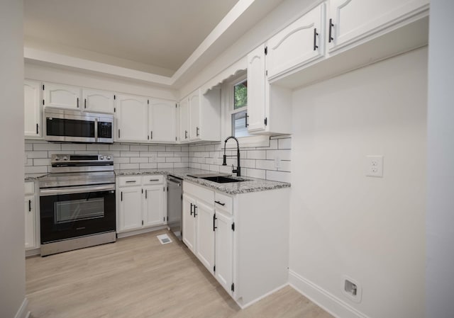 4037 Calumet Dr, Antioch, TN 37013 - kitchen with appliances with stainless steel finishes, white cabinets, decorative backsplash, light stone counters, and light wood-type flooring