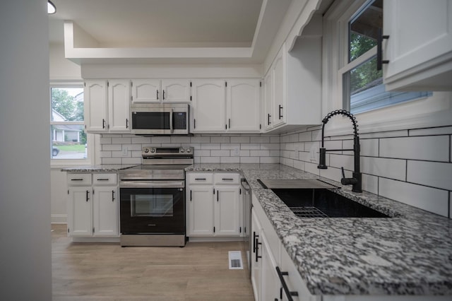 4037 Calumet Dr, Antioch, TN 37013 - kitchen with appliances with stainless steel finishes, backsplash, light wood-type flooring, and white cabinetry