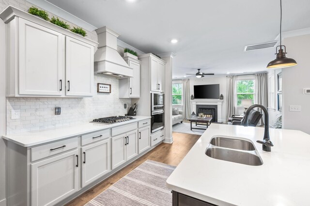 141 Foxhall Dr, Spring Hill, TN 37174 - kitchen with ceiling fan, open floor plan, a fireplace, light wood-style flooring, and custom exhaust hood