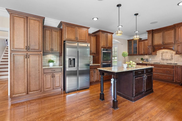 1005 Brittain Downs Dr, Nolensville, TN 37135 - kitchen with appliances with stainless steel finishes, arched walkways, decorative backsplash, wood finished floors, and a center island