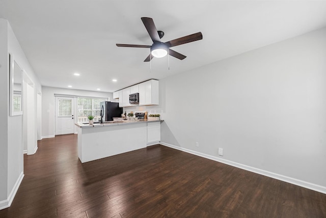 758 Spees Dr, Clarksville, TN 37042 - kitchen with freestanding refrigerator, a peninsula, black microwave, a ceiling fan, and dark wood-type flooring