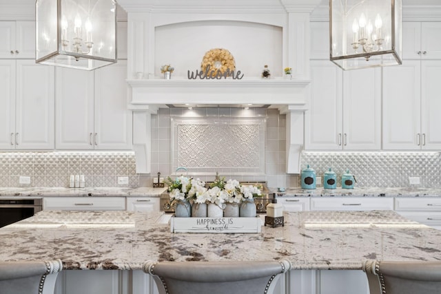 813 Stonewater Blvd, Franklin, TN 37064 - kitchen with white cabinetry, backsplash, a breakfast bar, and a chandelier