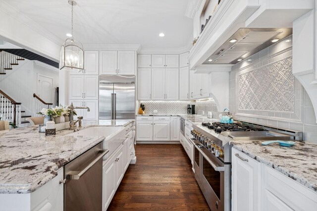 813 Stonewater Blvd, Franklin, TN 37064 - kitchen with high end appliances, wall chimney exhaust hood, white cabinets, decorative backsplash, and hanging light fixtures