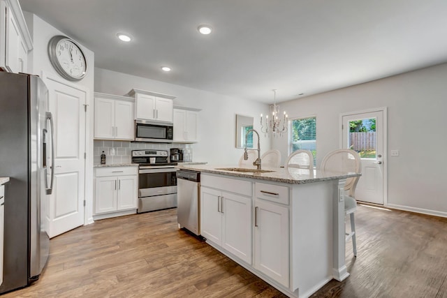 4112 Cadence Dr, Spring Hill, TN 37174 - kitchen featuring appliances with stainless steel finishes, a chandelier, light wood finished floors, white cabinets, and backsplash