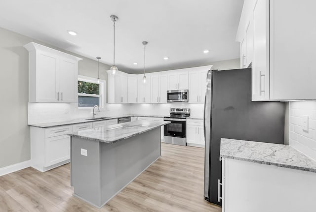 582 Pongracz Way, Clarksville, TN 37042 - kitchen with appliances with stainless steel finishes, a center island, decorative backsplash, white cabinetry, and light wood-type flooring