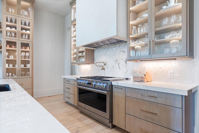 8227 Heirloom Blvd, College Grove, TN 37046 - kitchen with stainless steel stove, premium range hood, light wood-type flooring, light stone counters, and decorative backsplash