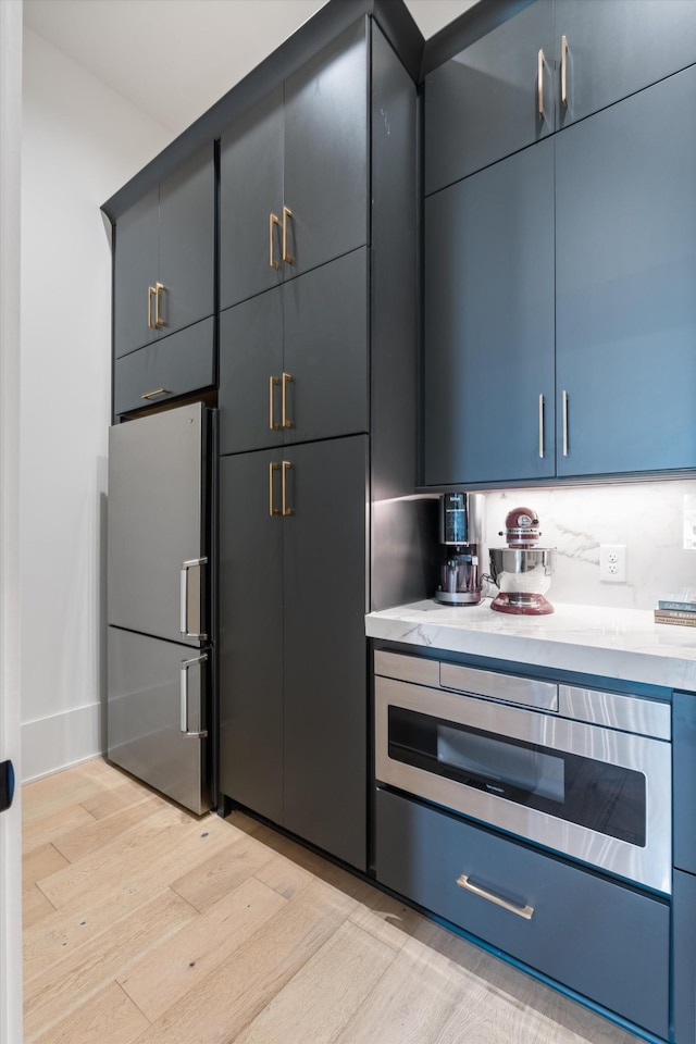 8227 Heirloom Blvd, College Grove, TN 37046 - kitchen with freestanding refrigerator, light wood finished floors, a warming drawer, and blue cabinetry
