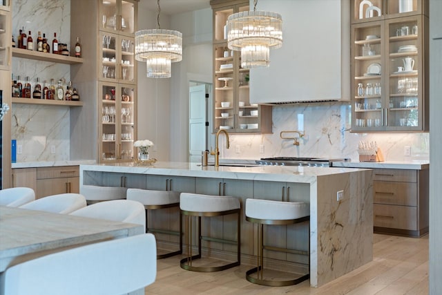8227 Heirloom Blvd, College Grove, TN 37046 - kitchen featuring light wood-style floors, decorative backsplash, a chandelier, a kitchen island with sink, and a breakfast bar